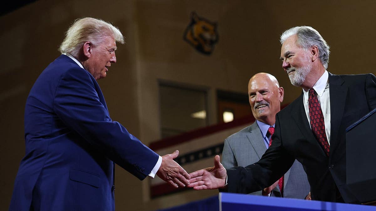 Donald Trump shakes hands with Mike Plant on stage at Wheeler High School in Marietta, Georgia.