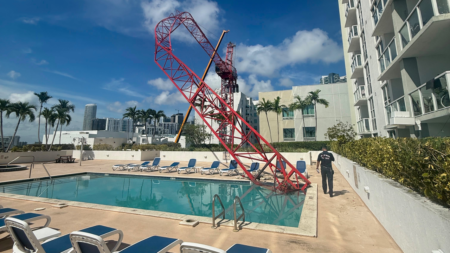 Crane arm collapses into Miami condo rooftop pool area as workers cling to dangling structure