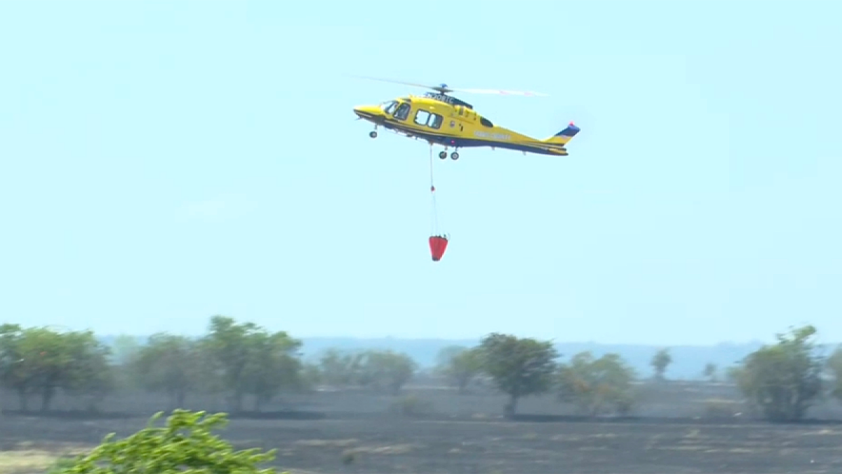 Firefighting helicopter carries water bucket over wildfire near deadly military helicopter crash in Salado, Texas