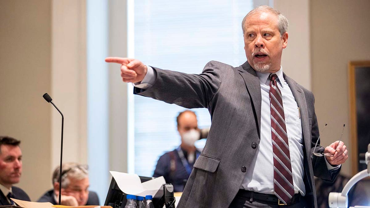 A man wearing a suit points inside of a courtroom.
