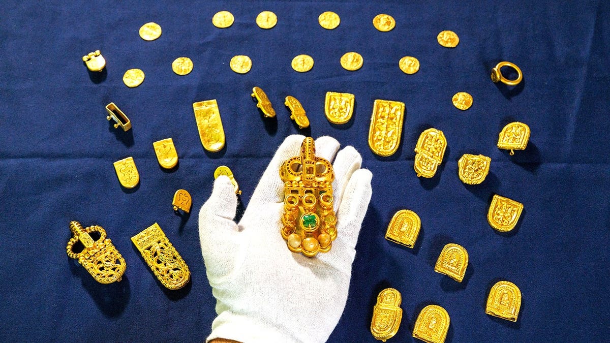Curator holding variety of gold jewelry from shipwreck