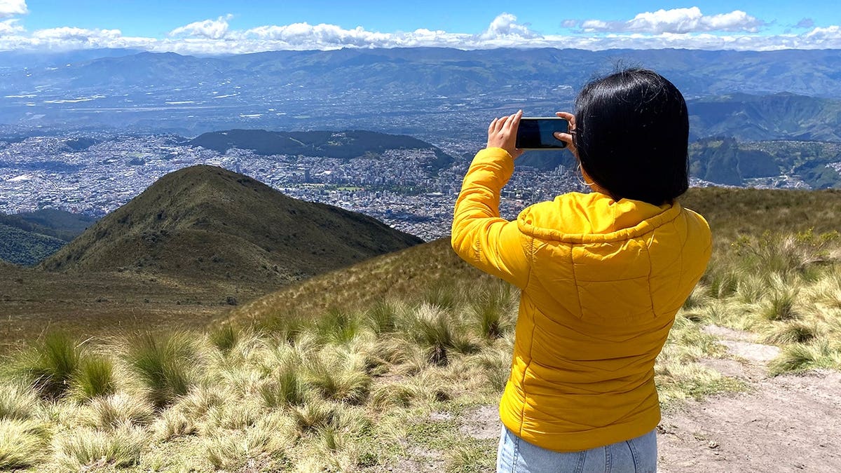 Woman taking picture of valley in Ecuador