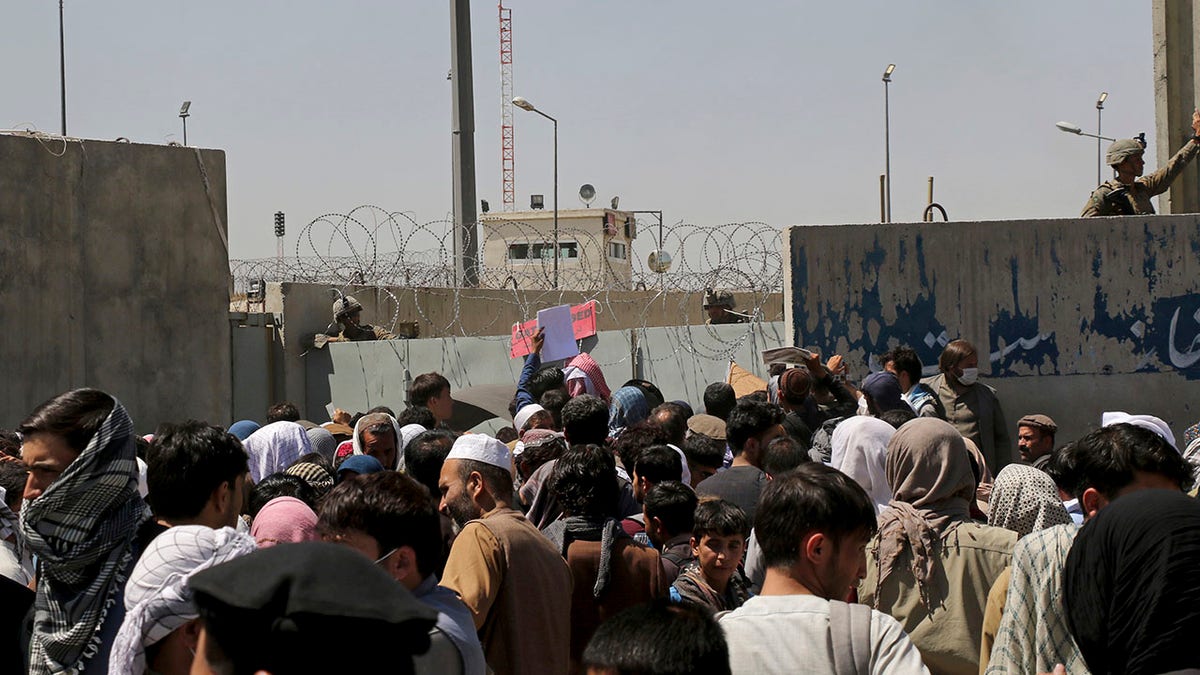 U.S. soldiers stand inside the airport wall as hundreds of people gather near an evacuation control checkpoint on the perimeter of the Hamid Karzai International Airport, in Kabul, Afghanistan, Thursday, Aug. 26, 2021. Western nations warned Thursday of a possible attack on Kabul's airport, where thousands have flocked as they try to flee Taliban-controlled Afghanistan in the waning days of a massive airlift. Britain said an attack could come within hours. (AP Photo/Wali Sabawoon)