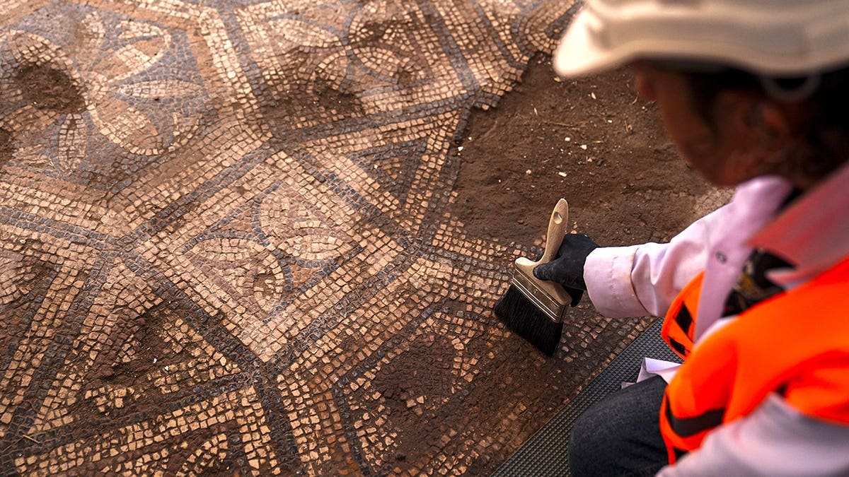 Archaeologist brushing ancient mosaic