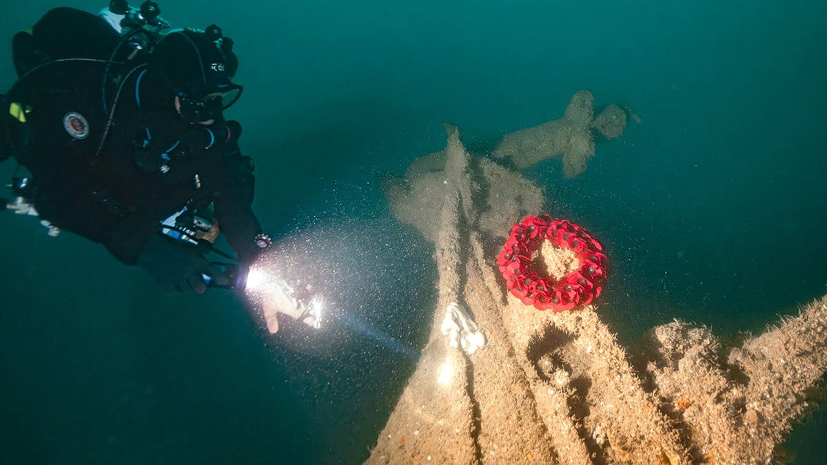 Diver inspecting Royal Navy ship and wreath
