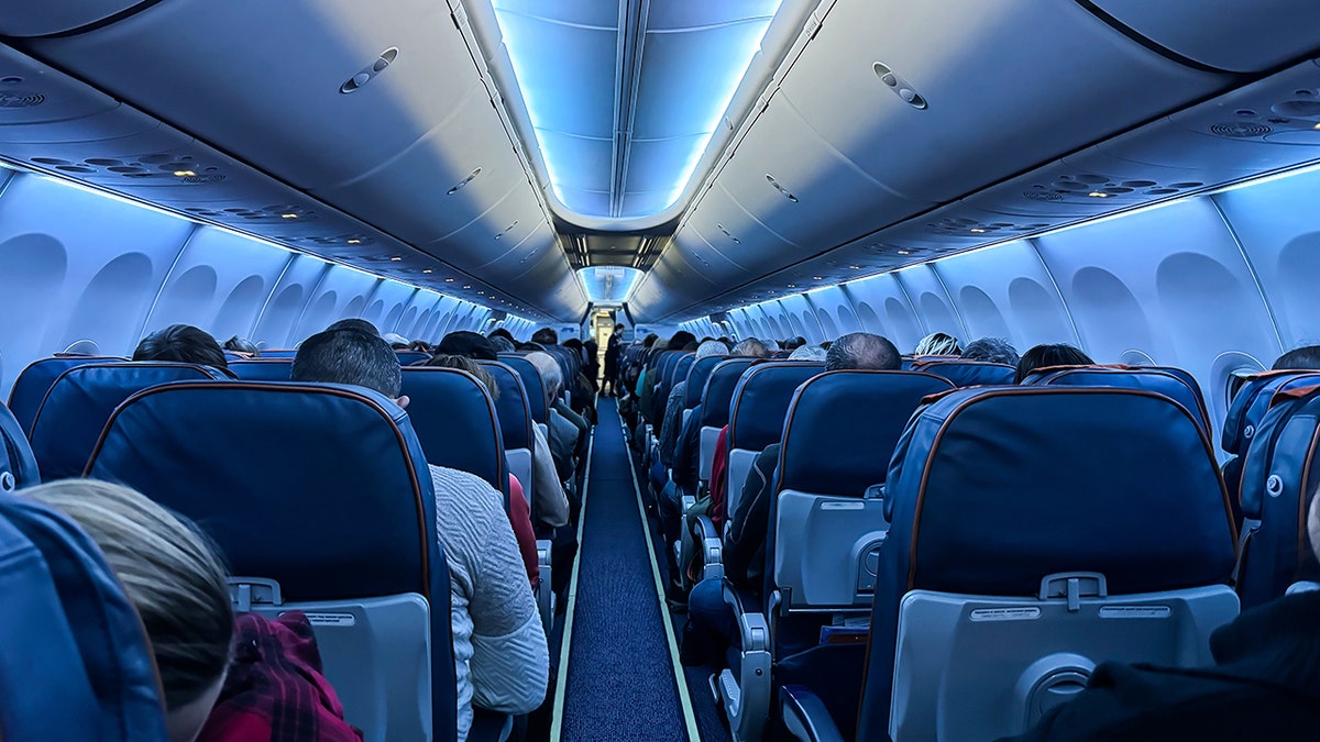 Interior of a commercial airplane cabin with passengers seated during a flight.