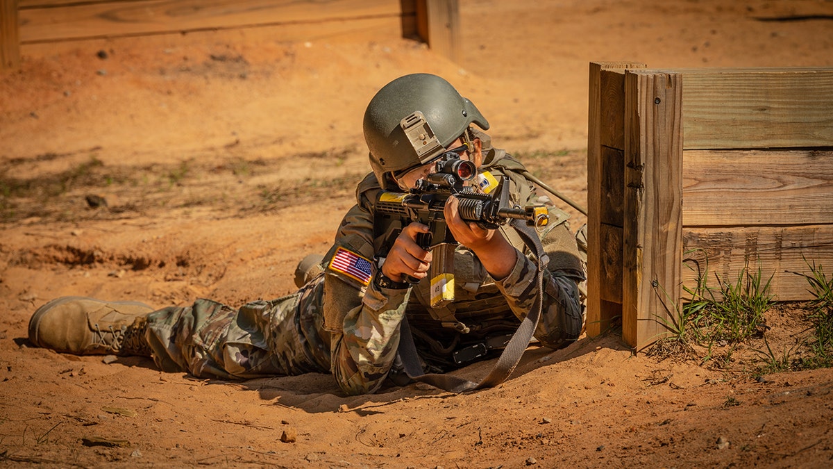 A recruit holds a gun and aims.