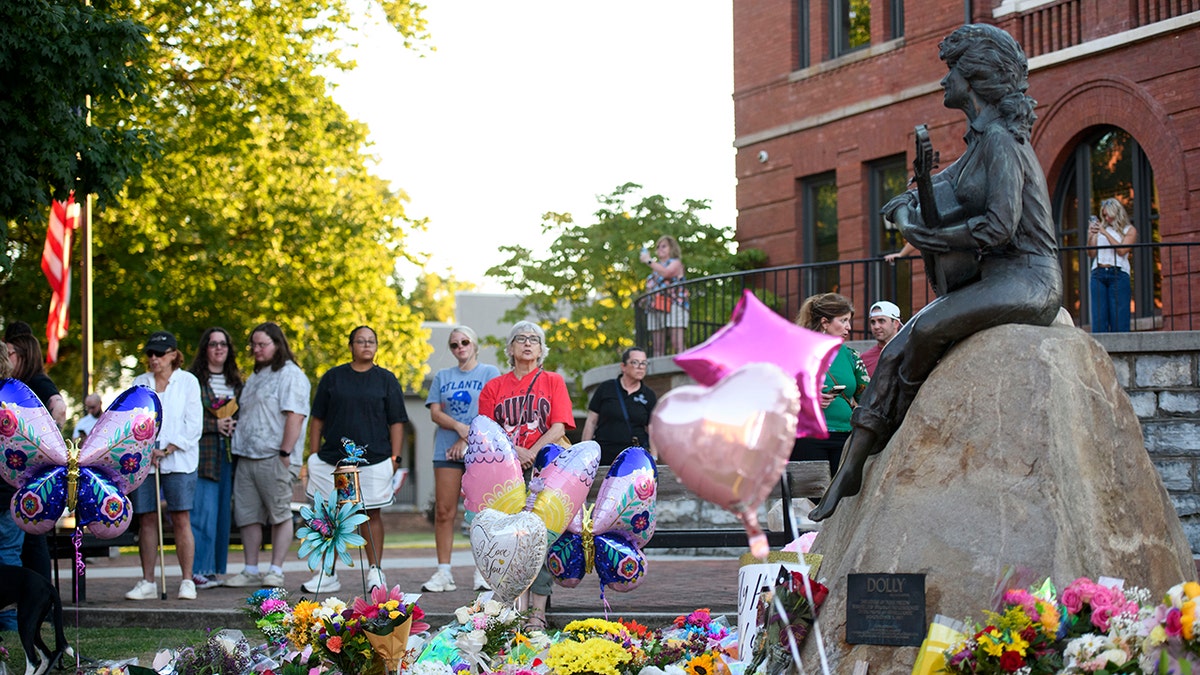 SEVIERVILLE, TENNESSEE - AUGUST 25: Fans pay tribute to Dolly Parton at her statue situated on the lawn at the Sevier County Courthouse on August 25, 2026 in Sevierville, Tennessee. The beloved country and crossover music superstar died after a brief battle with cancer, according to a statement by representatives today. She was 80. (Photo by Melissa Sue Gerrits/Getty Images)