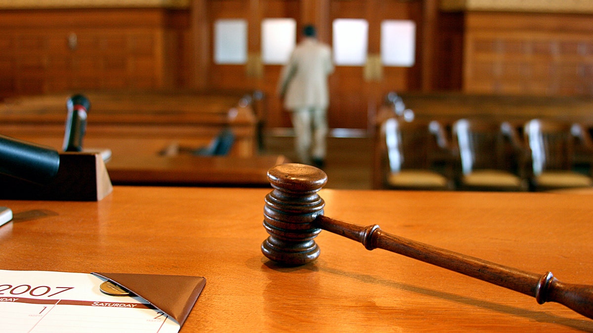 A gavel on a bench as people leave court