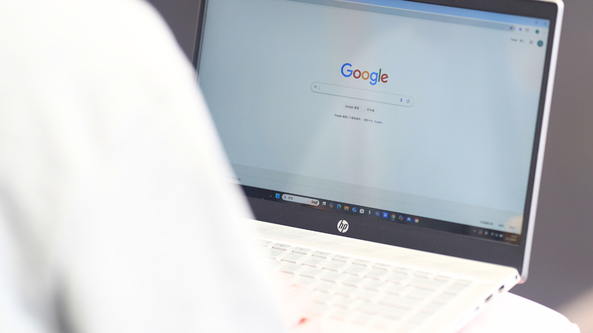 A woman browses the website Google on a laptop.