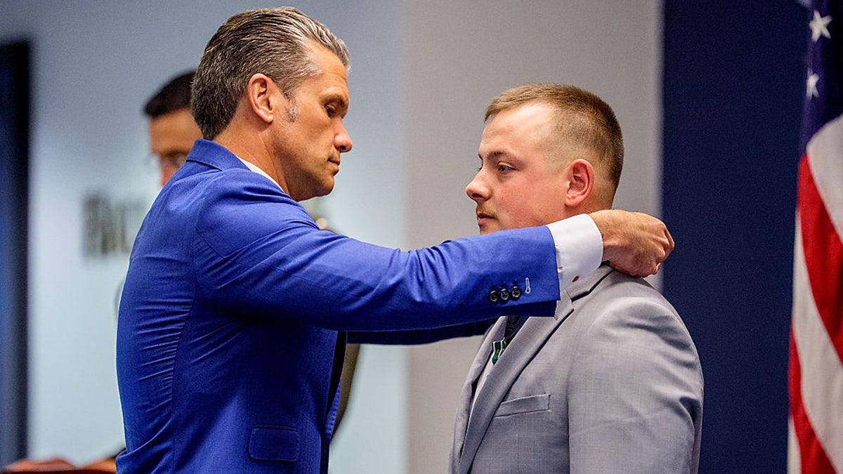 Secretary of War Pete Hegseth puts a medal on Marine Cpl. Michael Gretzon during an event to honor Marines, who were serving during the 2021 Abbey Gate bombing, at the Pentagon, Wednesday, in Arlington, Va.