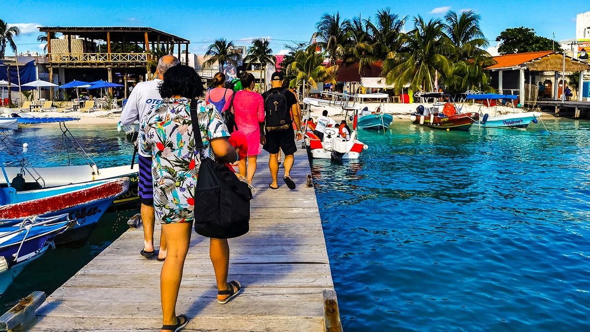 Boats and yachts sit near a jetty pier in turquoise water off Isla Mujeres island in Cancun.
