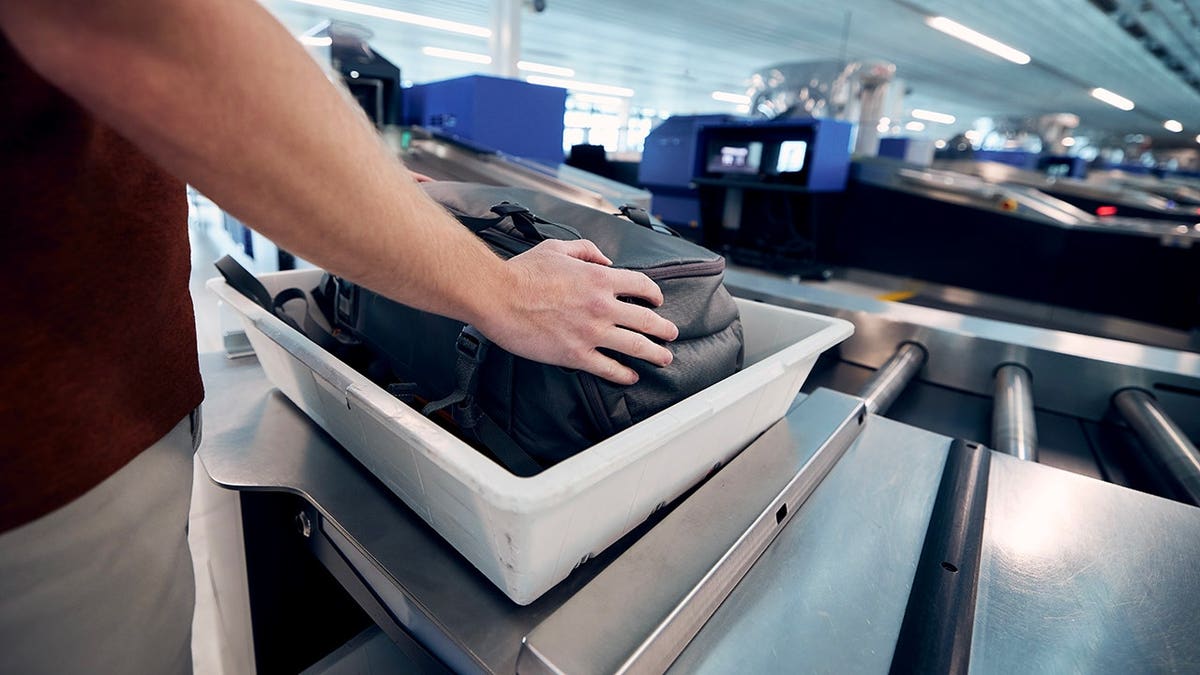 Young man waits with his bag at airport security screening.
