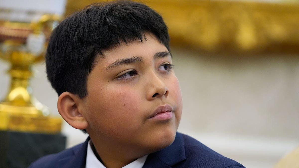 Nathaniel Rai listens as President Donald Trump meets with lifeguard Ryder Williams in the Oval Office.