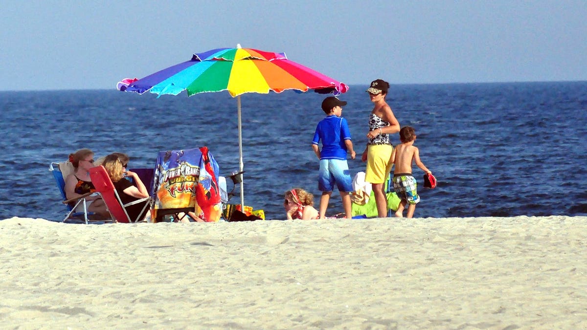 Family with rainbow umbrella on NJ beach