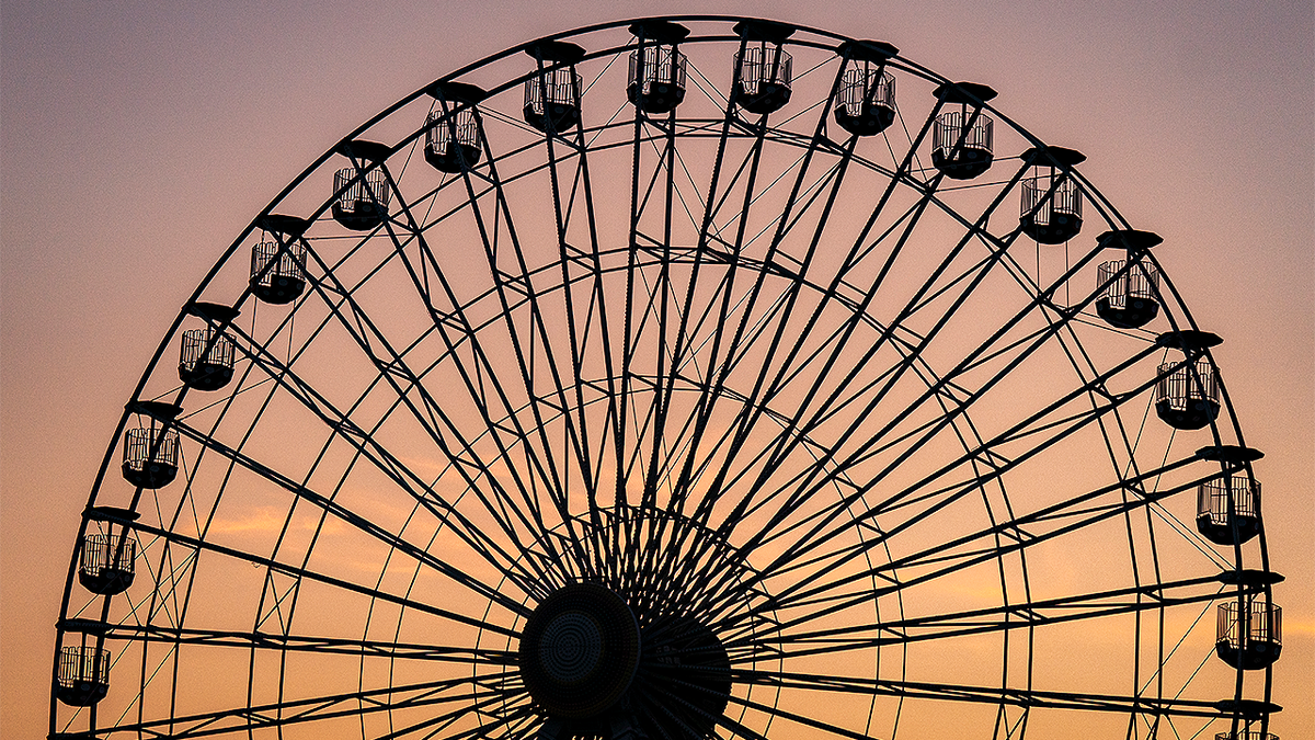 The Ferris wheel at the Ocean City, New Jersey, boardwalk is silhouetted against a sunset sky