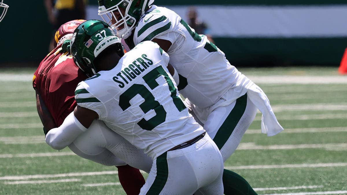 Qwan'tez Stiggers and Charles Surratt of the New York Jets make a defensive stop during a game.