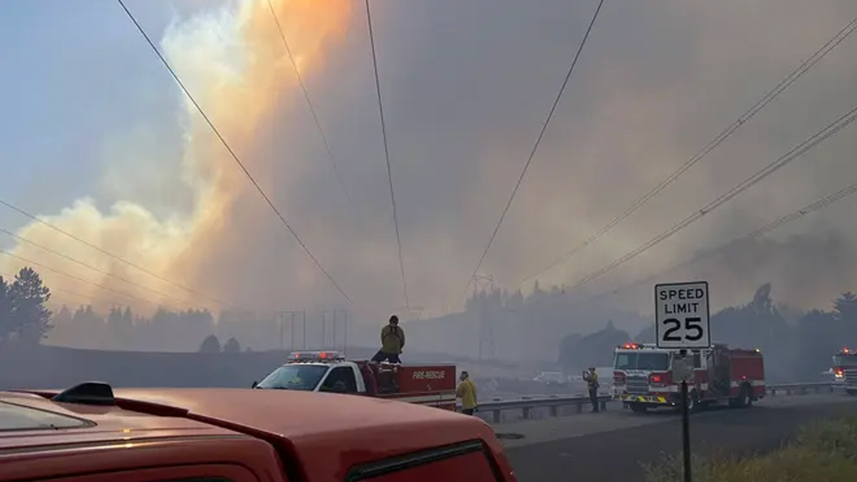 Firefighters respond beneath a massive smoke plume during the Spokane-area wildfires