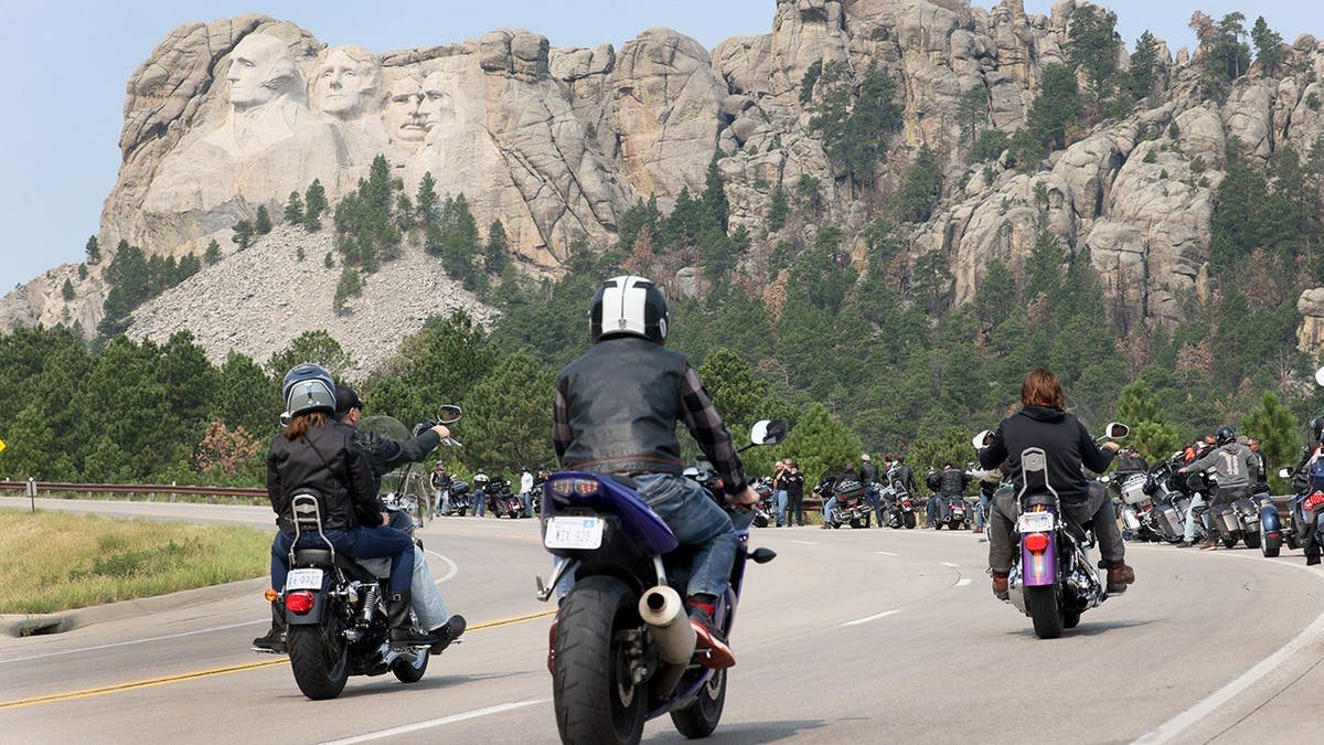 Motorcycle riders ride toward Mount Rushmore.