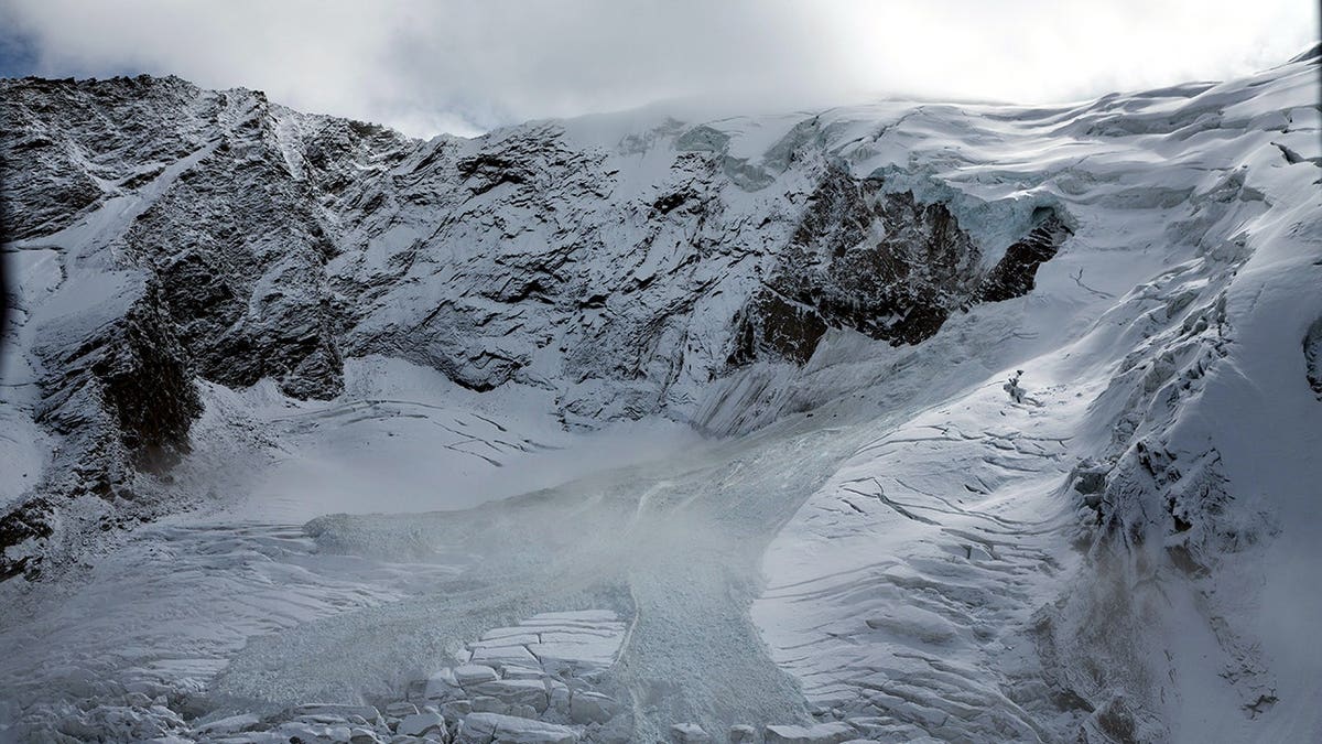 Glacial ice avalanche cascades from the Trift Glacier above a village in Saas-Grund, Switzerland.