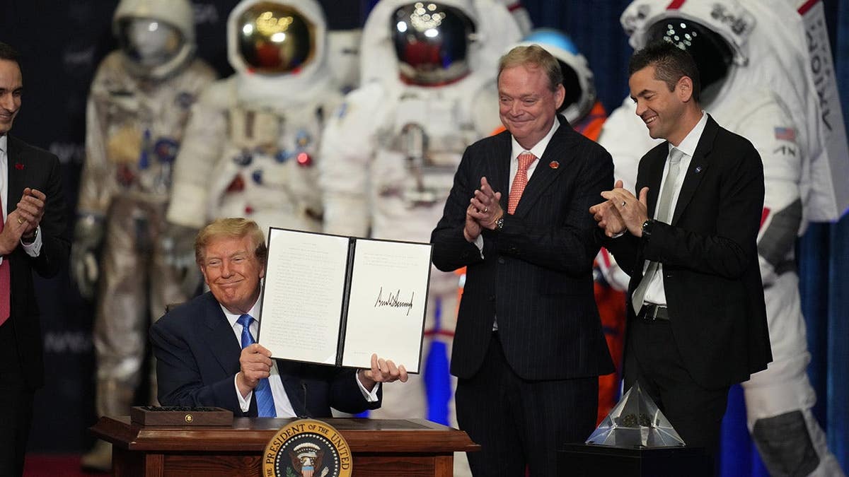 President Donald Trump stands at a Congressional Space Medal of Honor ceremony with Kevin Hassett and Jared Isaacman in Houston.