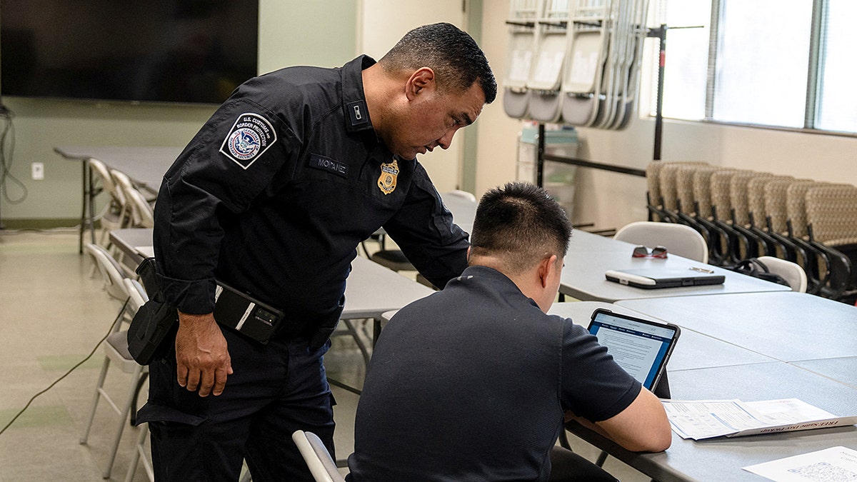 U.S. Customs and Border Protection (CBP) recruiter Gabriel Montanez helps a man fill out an application during a CBP and Border Patrol recruitment event at a public library in El Paso, Texas, U.S., September 25, 2025. REUTERS/Paul Ratje