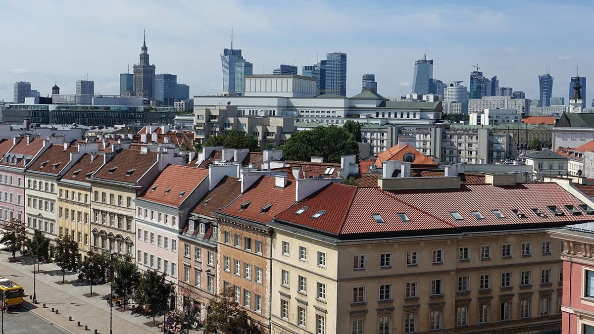 Krakowskie Przedmieście boulevard extends toward Warsaw's modern skyline.