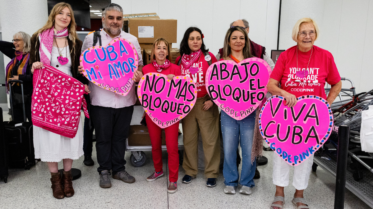 Medea Benjamin, co-founder of CodePink, holds a sign supporting Cuba at Miami International Airport on March 20, 2026, before a delegation travels to Cuba.