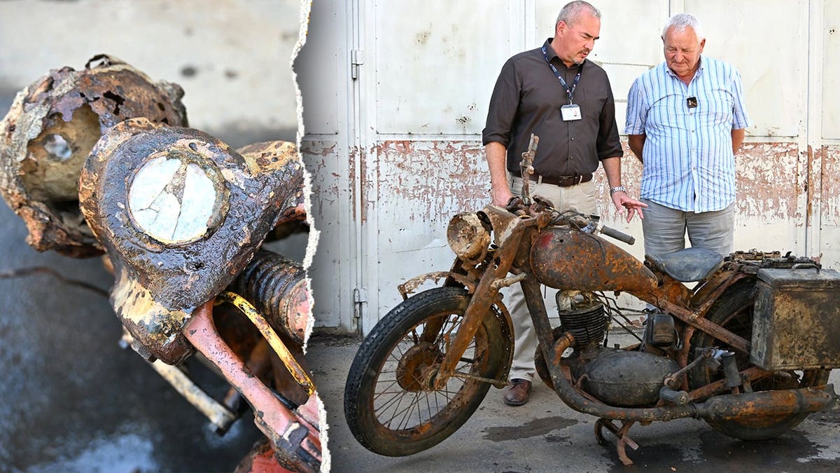 View of motorcycle next to two men inspecting it