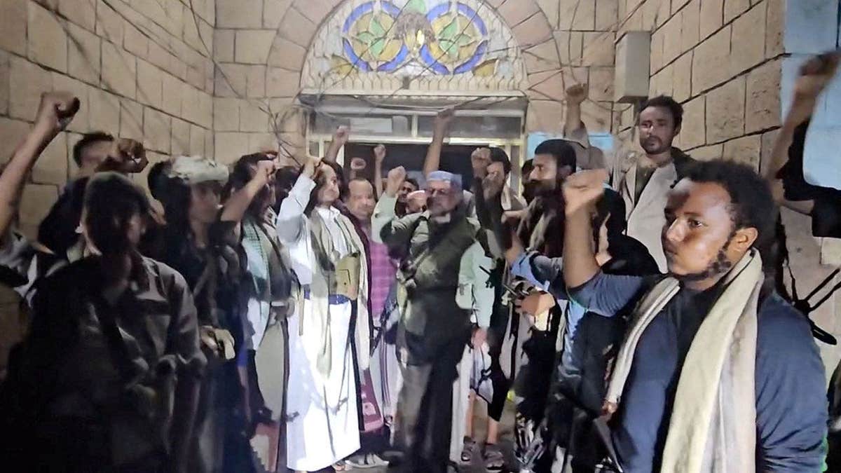 Houthi fighters gesture as they celebrate in front of the Security Directorate building in Hays, Yemen