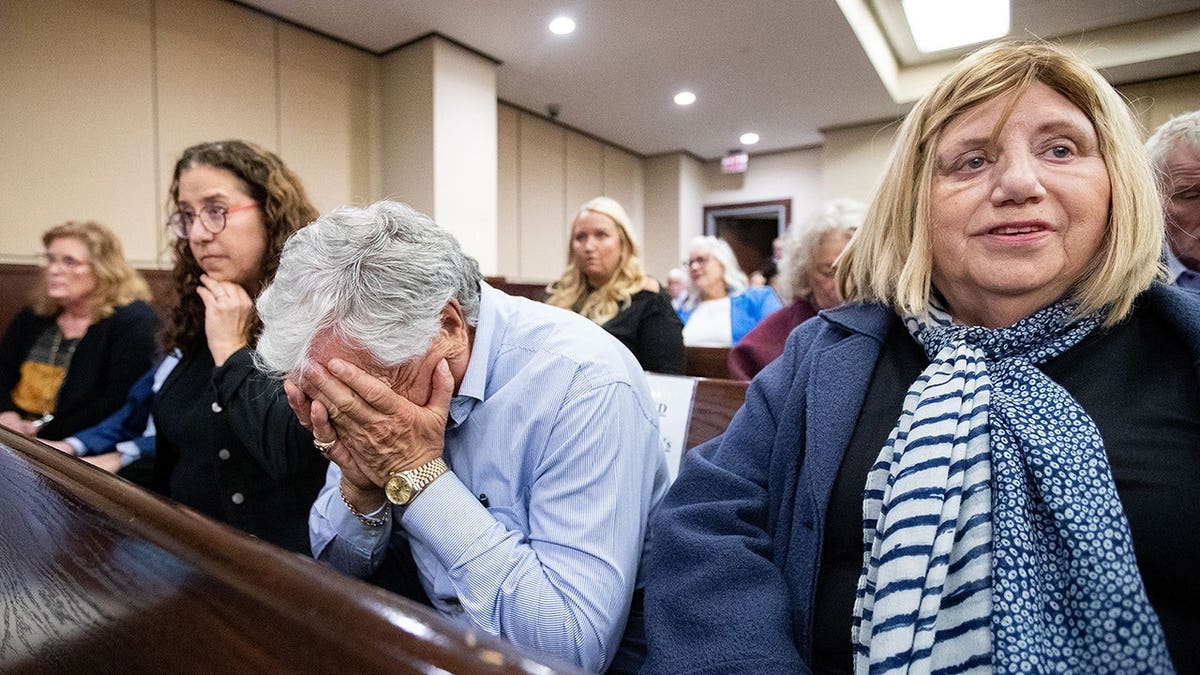 Phil Markel buries his face in his hands in a courtroom after hearing a guilty verdict.