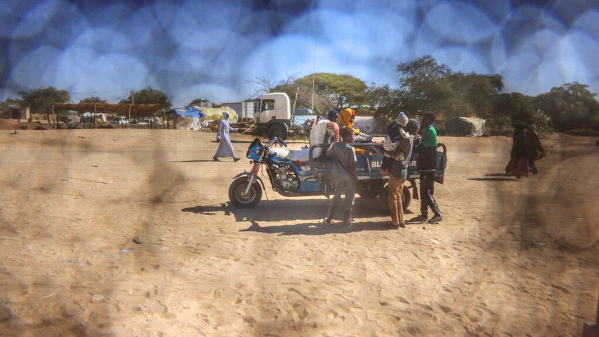 A Sudanese refugee father from Al-Fashir rides on a motorized cart with his family travelling between Chad and Sudan