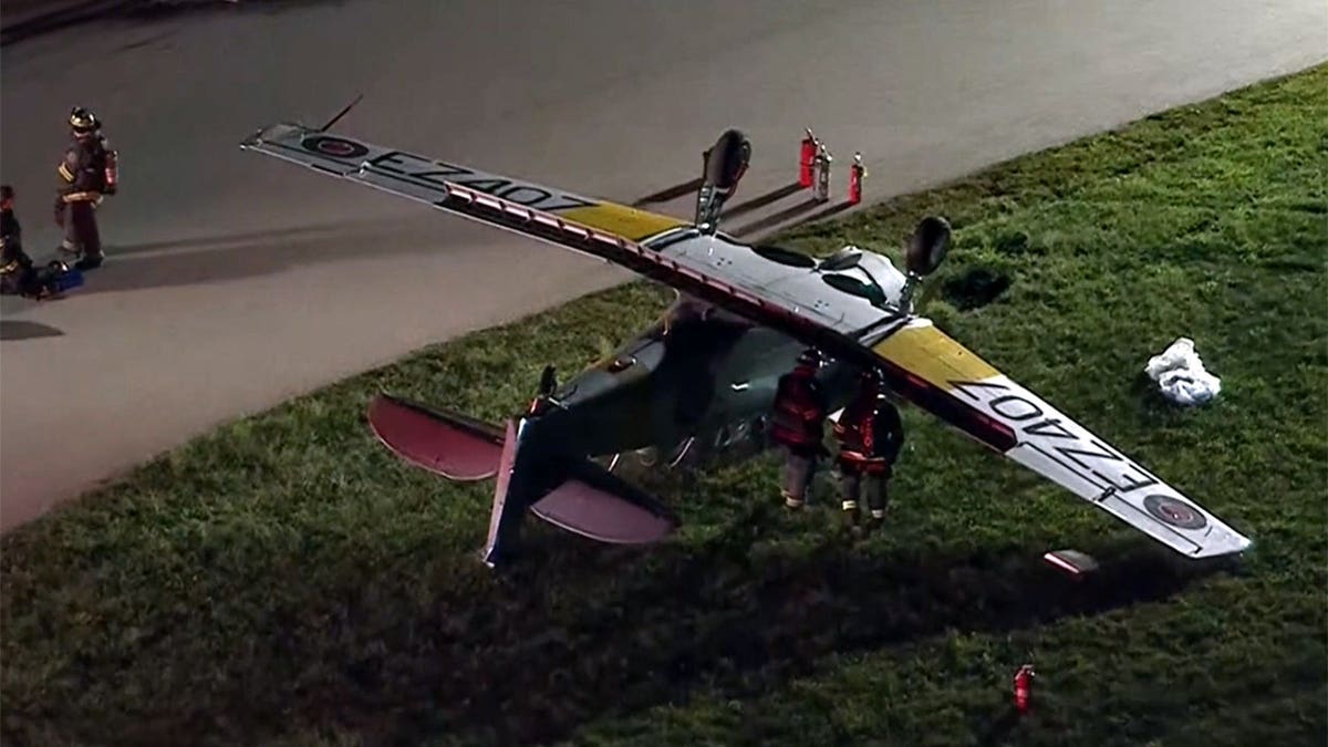 first responders stand near the overturned aircraft
