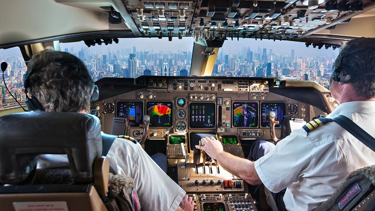 Cockpit of a modern passenger aircraft in flight with a view of city skyscrapers.