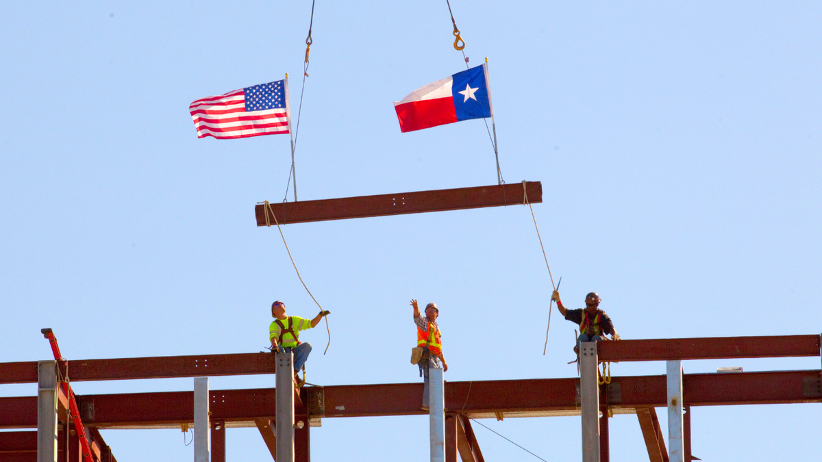 Workers place the last beam to finish the framing a building in a suburb of Dallas, Texas.