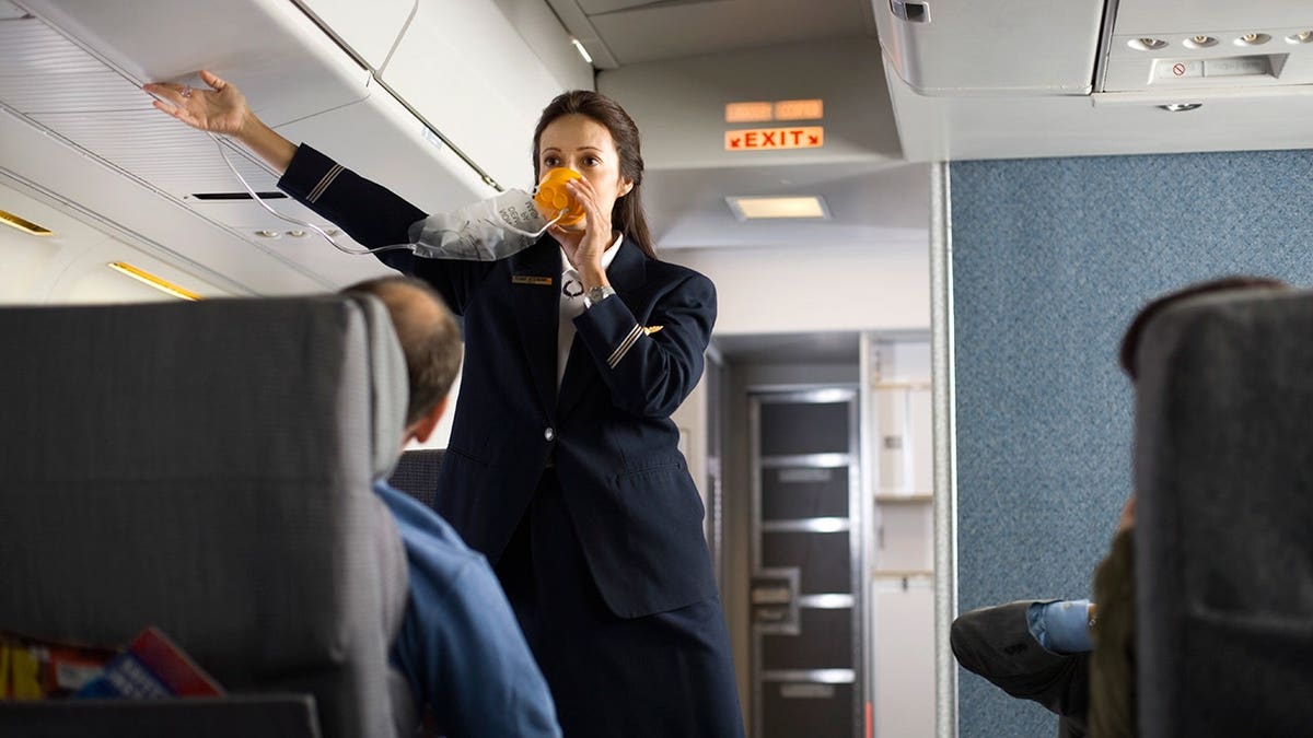 A flight attendant holding an oxygen mask.