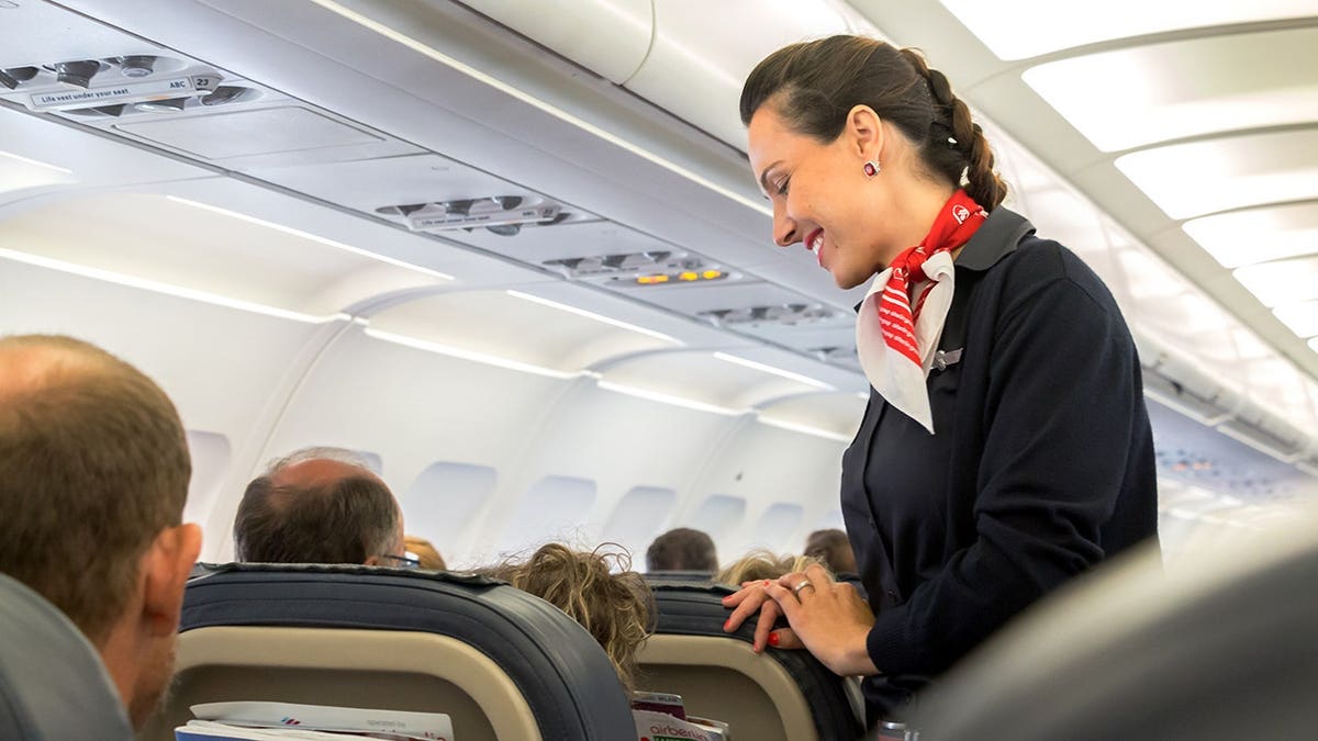 Flight attendant speaks with passenger in economy class on Eurowings flight.