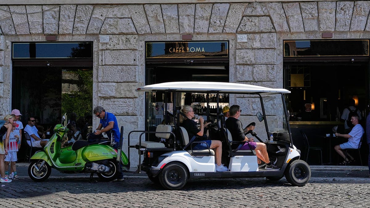 Golf cart carrying tourists travels through central Rome.