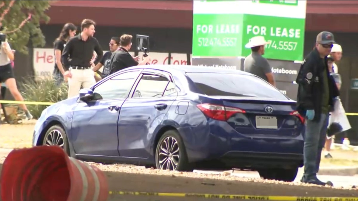 Authorities near a car at the scene of the shooting.