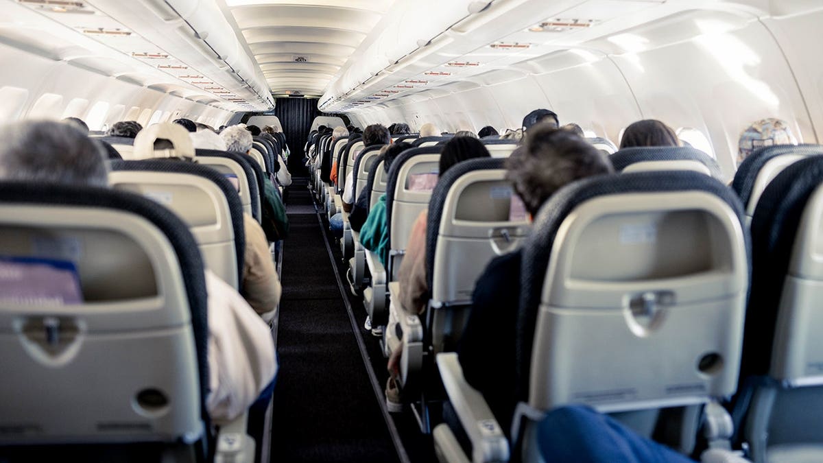 Interior of an aeroplane cabin showing rows of seats down the aisle