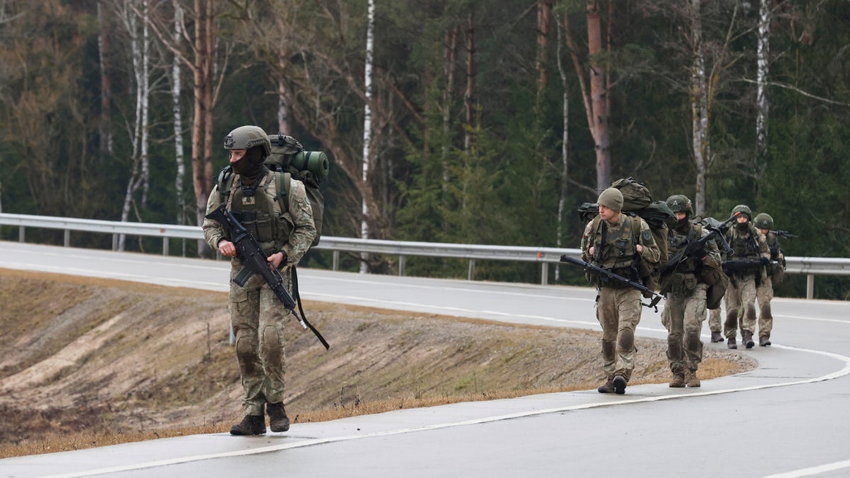 Soldiers walk along a road near a training range in Pabrade, north of the capital Vilnius, Lithuania on Thursday, March 27, 2025.