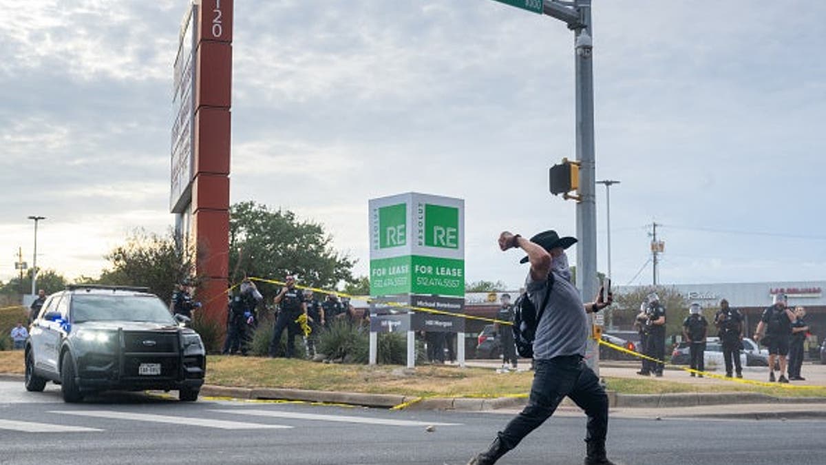A person throws a rock at law enforcement during an ICE protest in Austin, Texas.