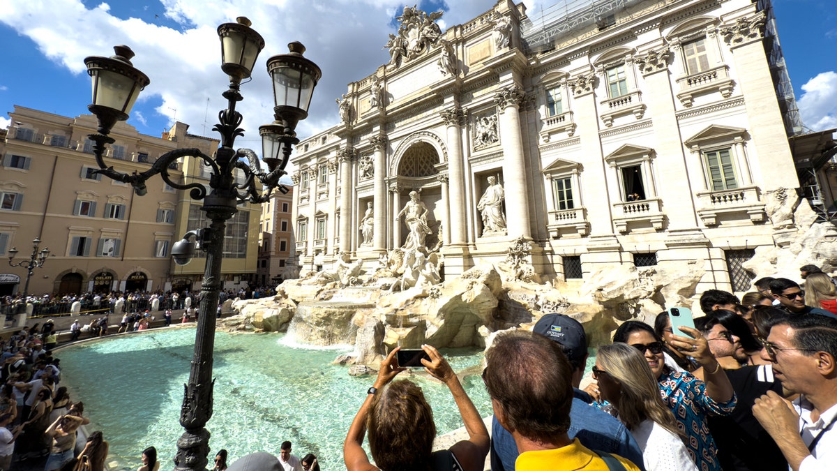 tourists crowd trevi fountain during the day