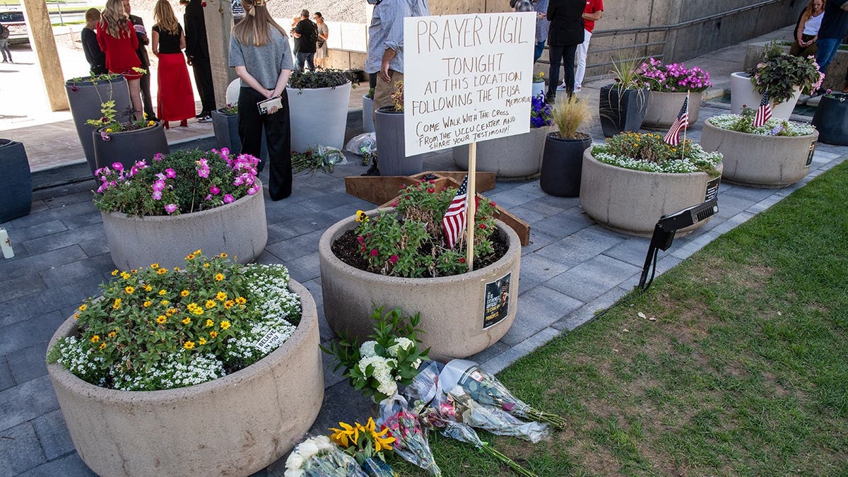 Floral tributes and a prayer vigil sign sit beside concrete planters at Utah Valley University in Orem, Utah.