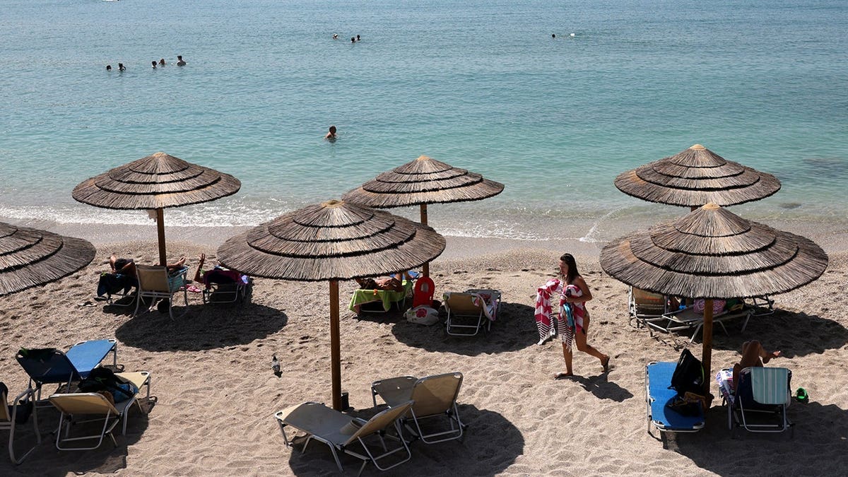 A woman walks on the beach in Vouliagmeni near Athens, Greece.